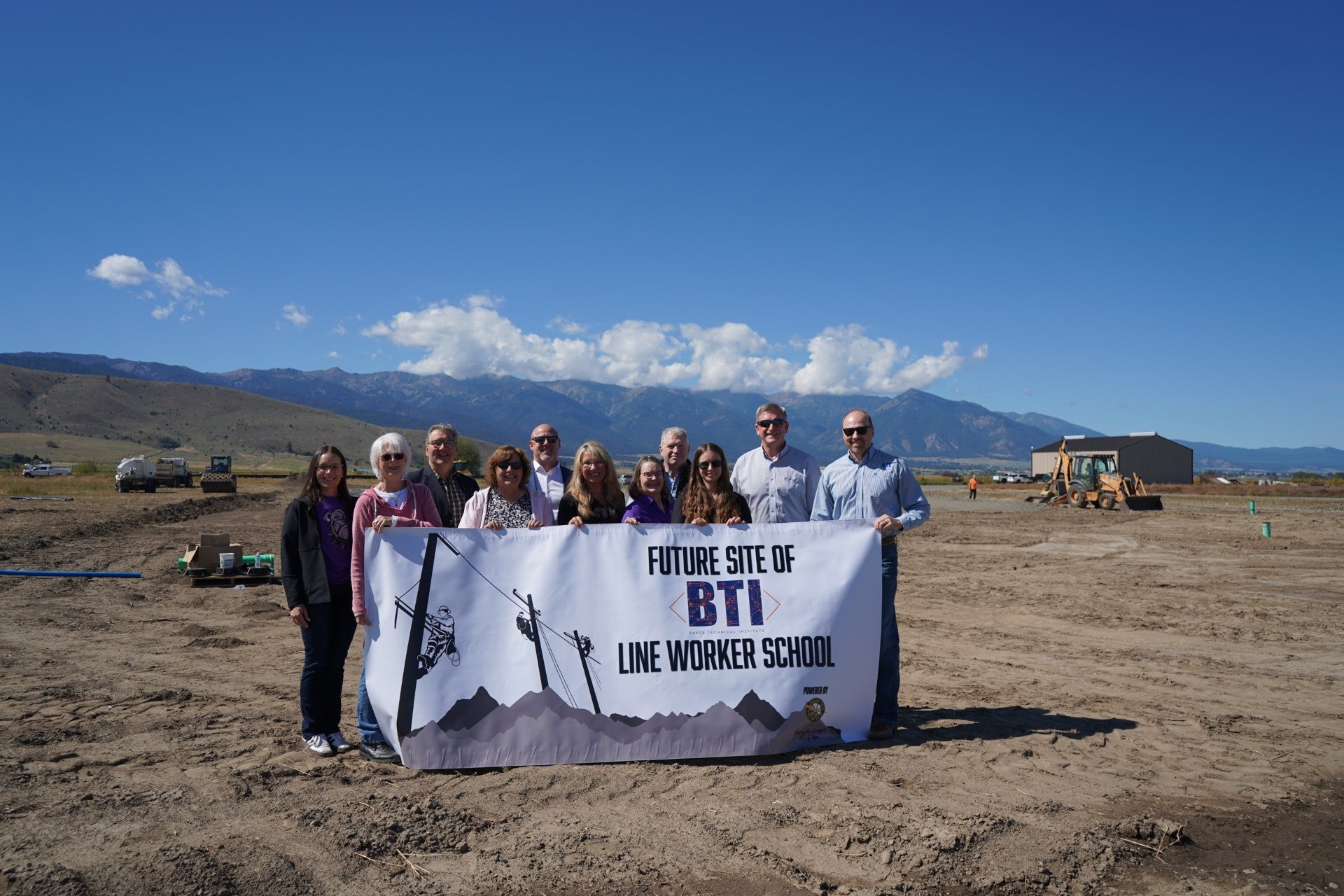 Oregon Trail Electric Cooperative Representatives and Baker Technical Institute Representatives hold banner at groundbreaking site for new line school.